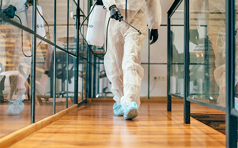 Man walking through office spray disinfectant